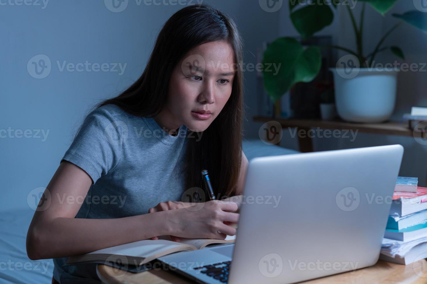 Wfh, asian young student woman making notes, study online of university, sitting on desk at home, doing homework connecting to internet on computer, studying late at night, learning and education. photo