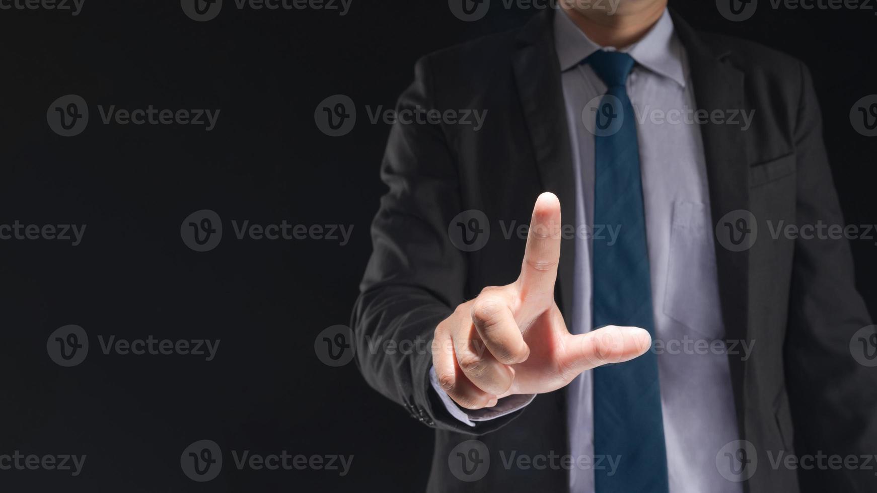 Businessman hand touching virtual screen on black background photo