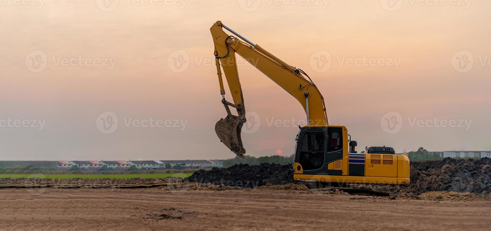 Excavator working on construction site at sunset background photo