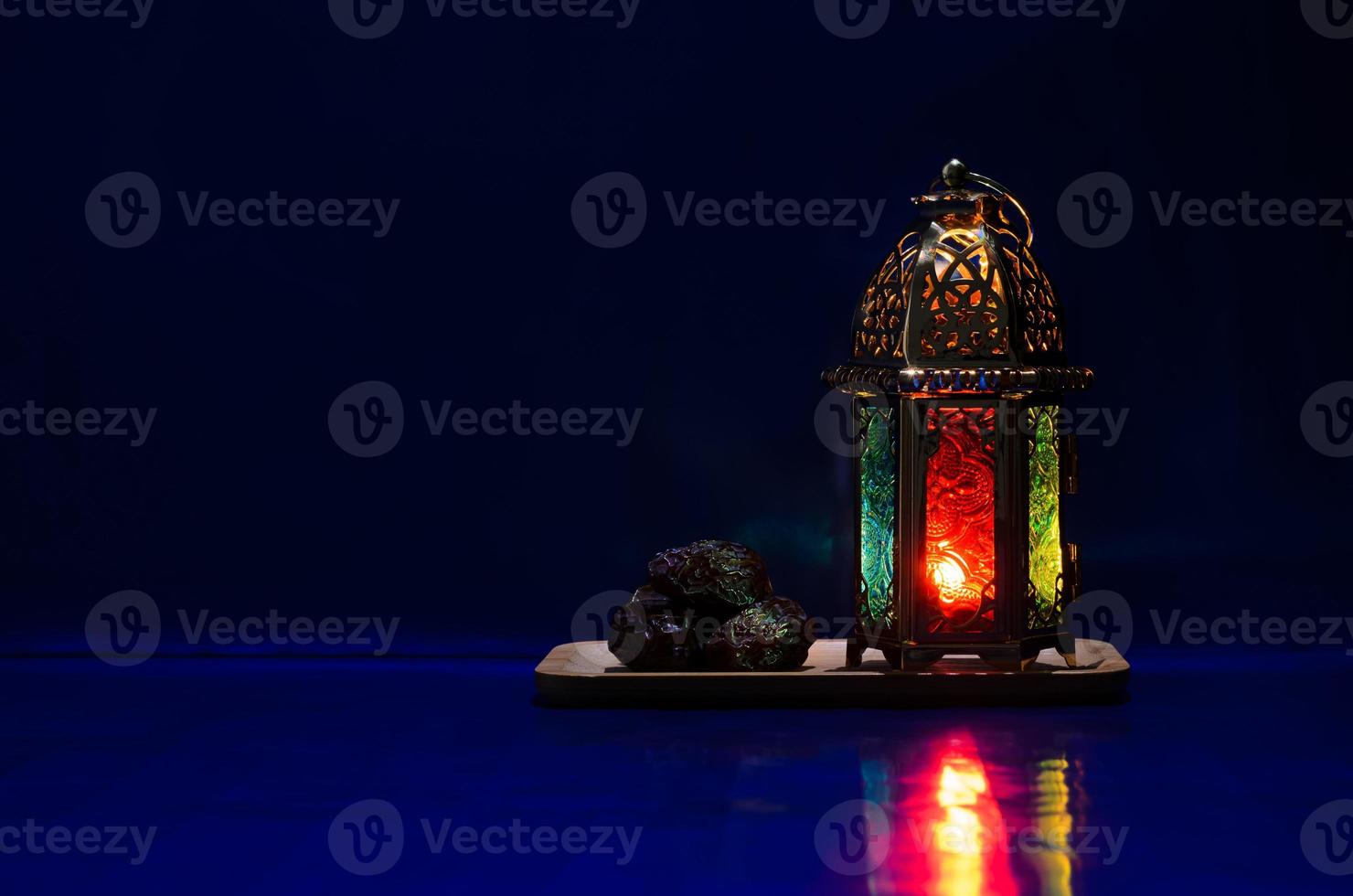 Lantern and dates fruit put on table with dark blue background for the Muslim feast of the holy month of Ramadan Kareem. photo