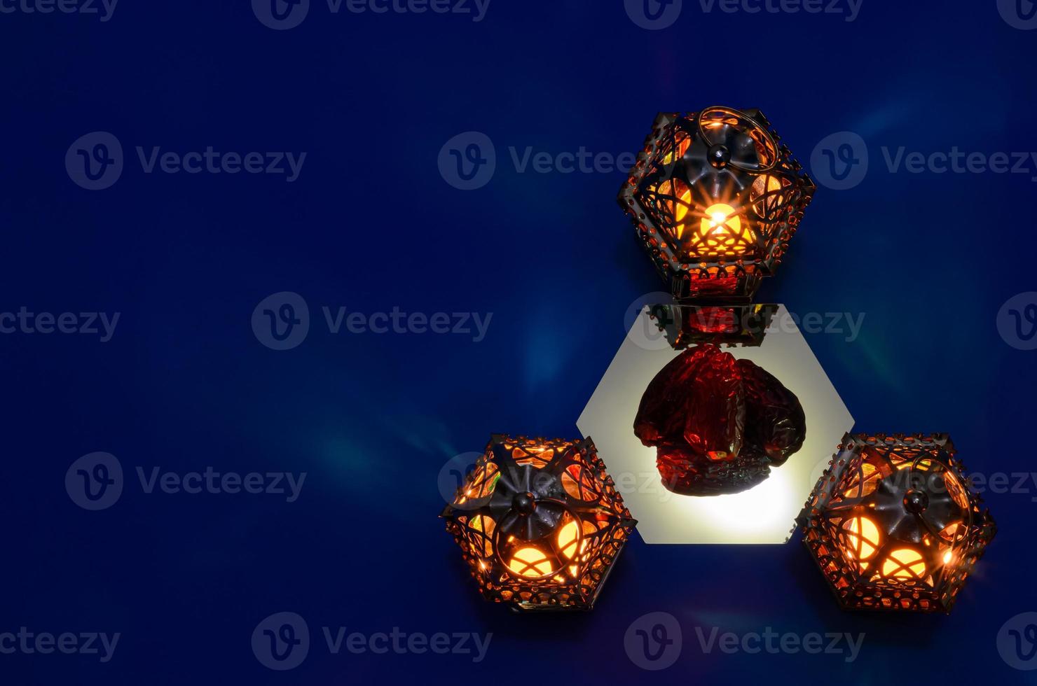 Selective focus on dates fruit with blurred lanterns put on mirror with blue background for the Muslim feast of the holy month of Ramadan Kareem. photo