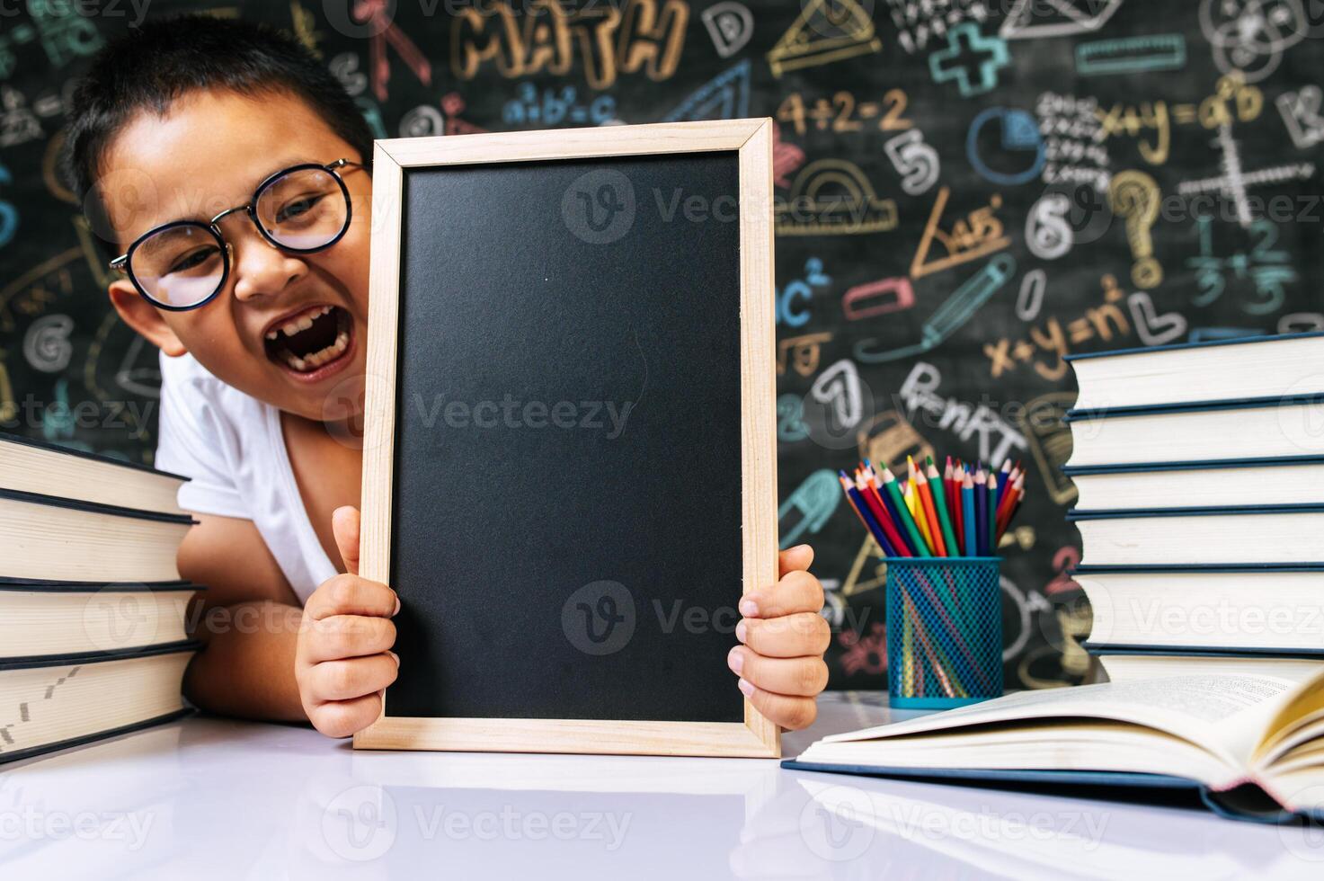 Child sitting and holding blackboard in the classroom photo