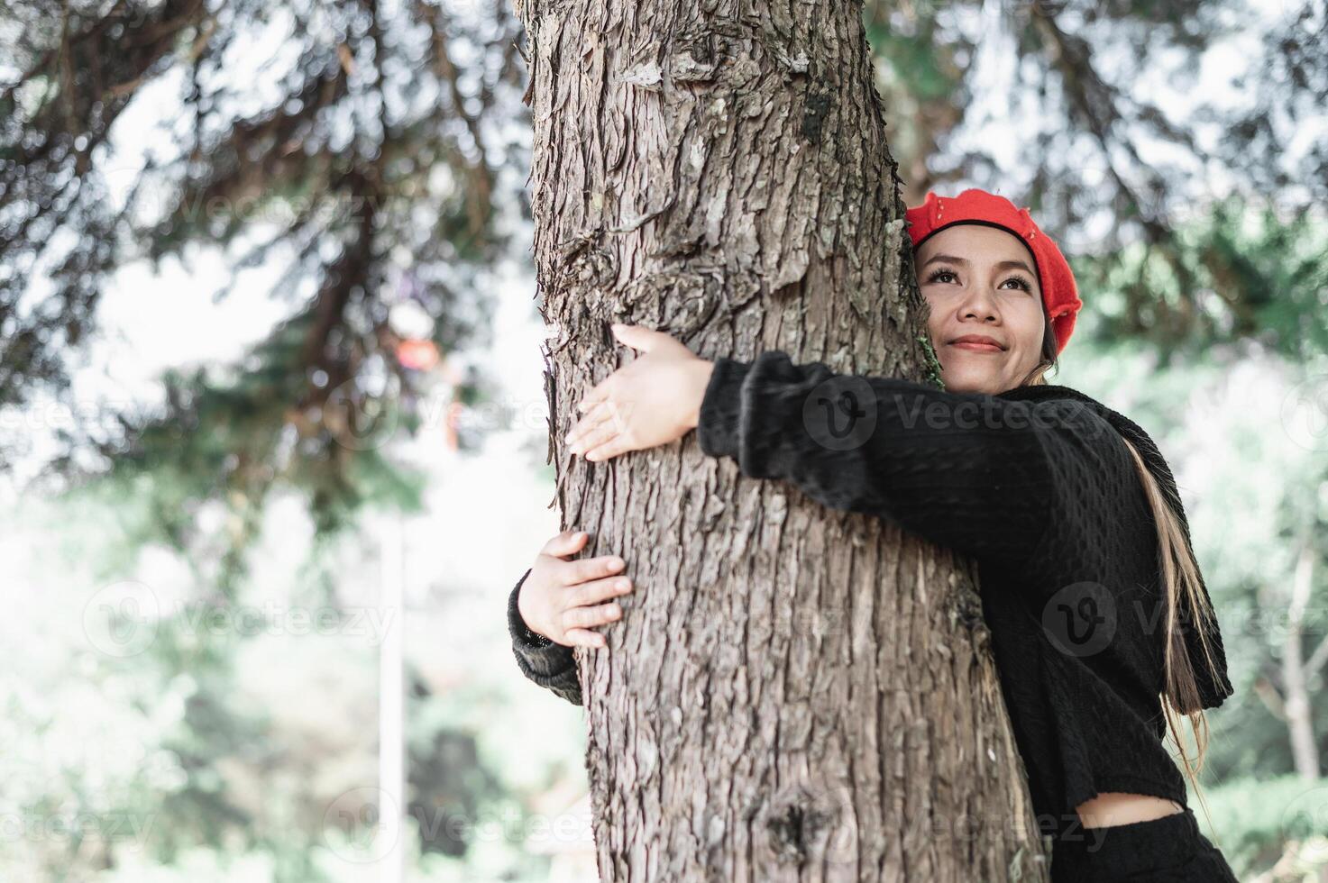 contento joven mujer abrazando un grande árbol con un feliz expresión con Copiar espacio foto