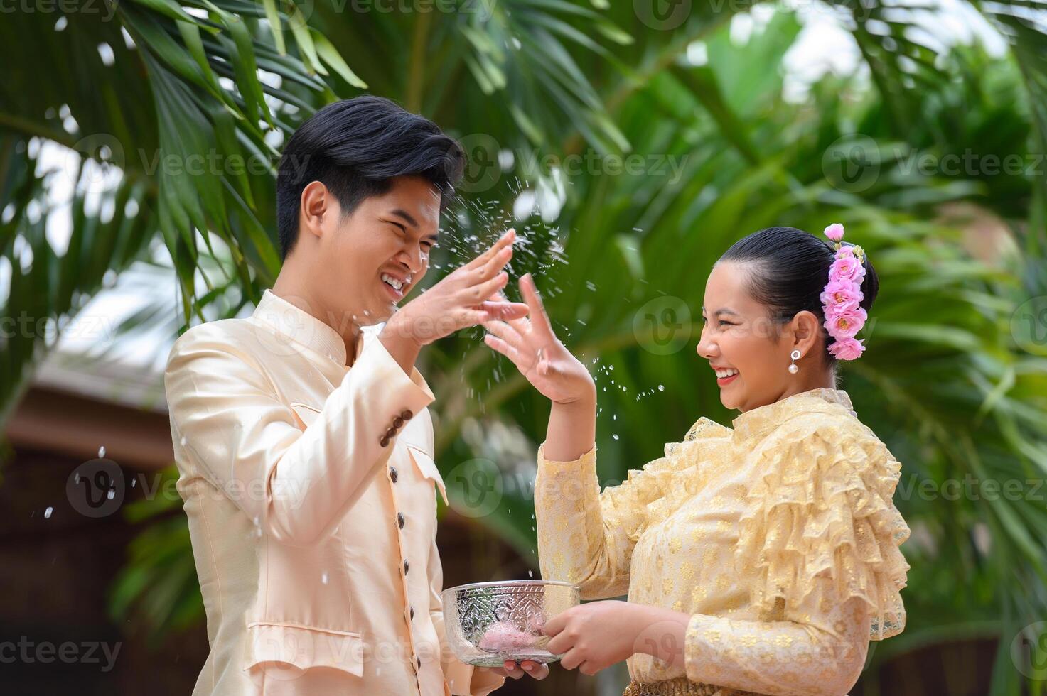 pareja joven salpicando agua del tazón en el festival de songkran foto