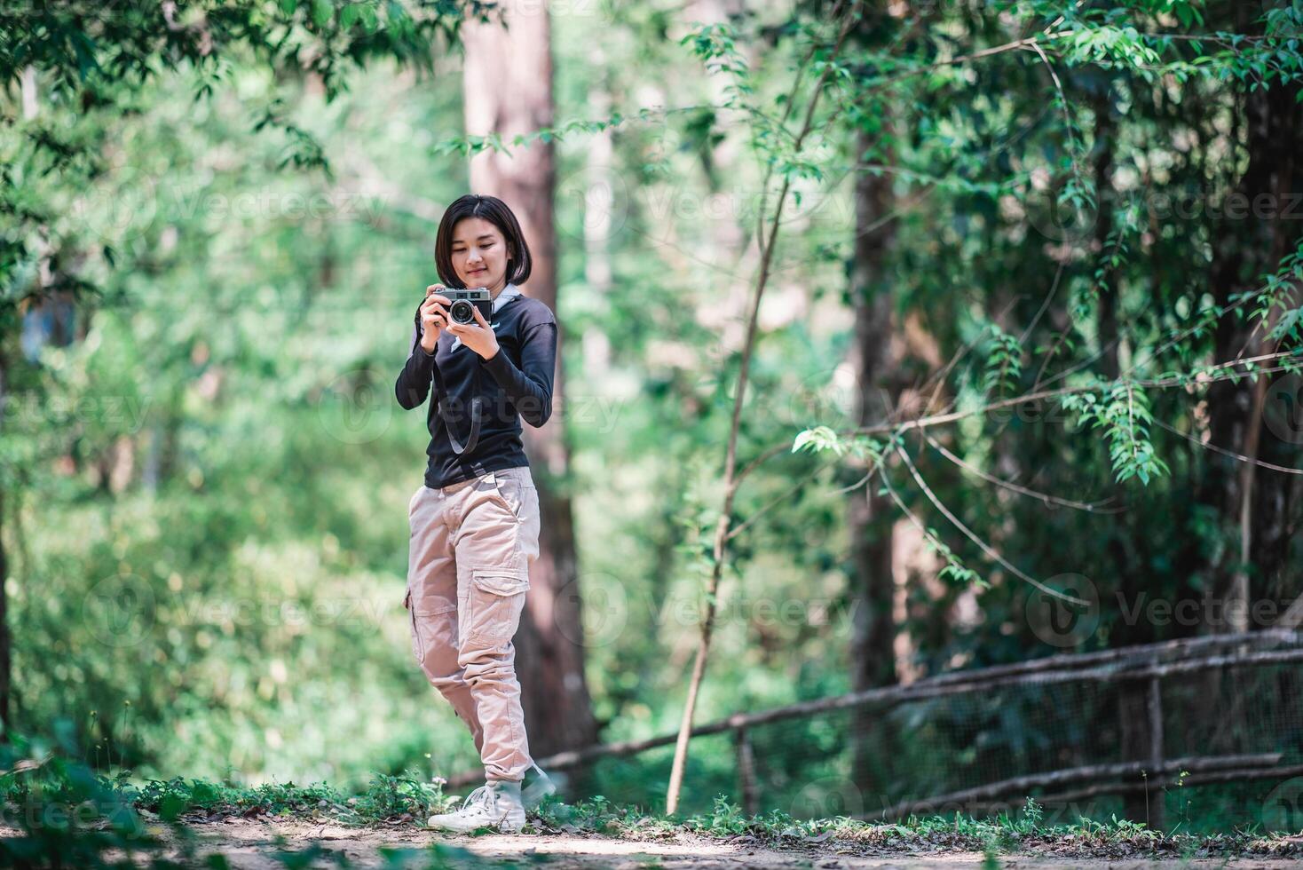 una mujer bonita joven usa una cámara para tomar fotos en un parque natural