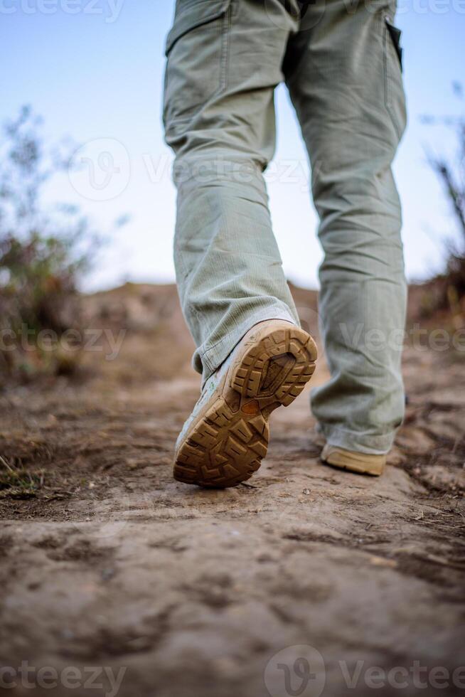 Close-up feet Hiker man wearing boots to travel walking in a green forest photo