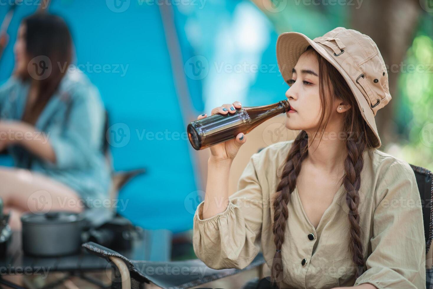 mujeres jóvenes animan y beben bebidas frente a la tienda de campaña foto