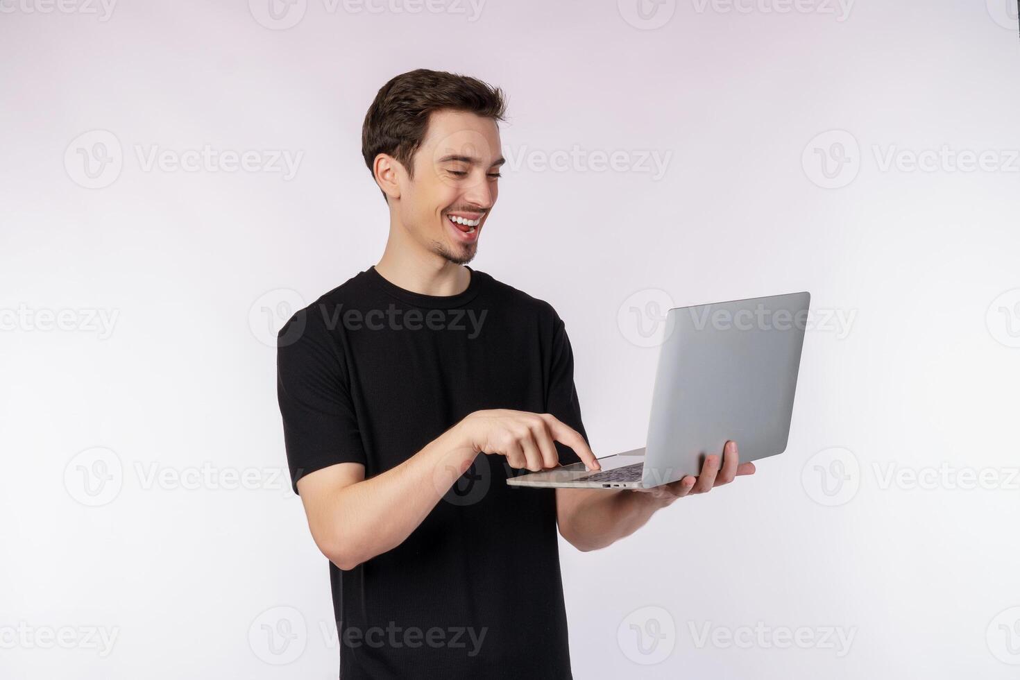 Portrait of young handsome smiling man holding laptop in hands, typing and browsing web pages isolated on white background photo