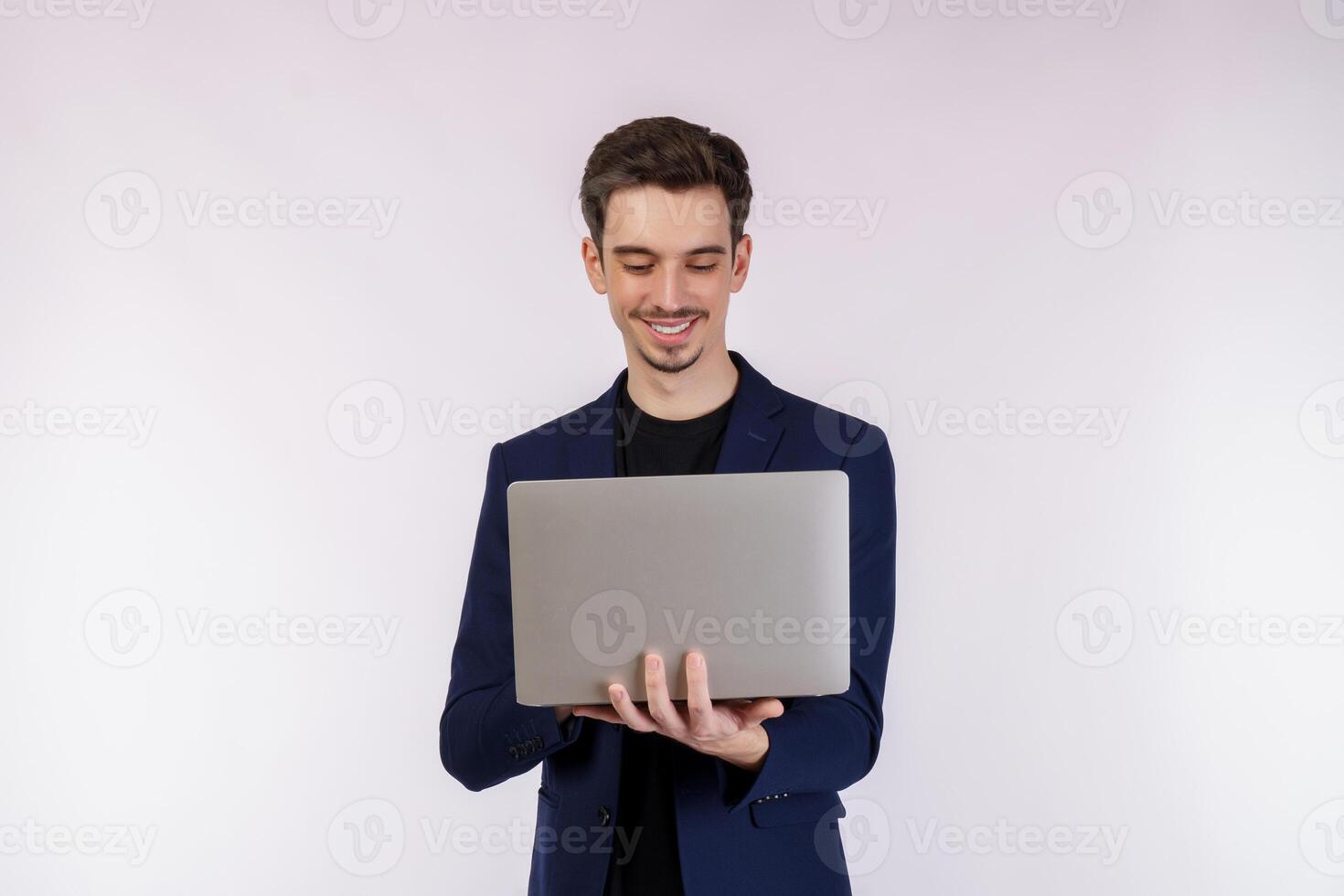 Portrait of young handsome smiling businessman holding laptop in hands, typing and browsing web pages isolated on white background photo