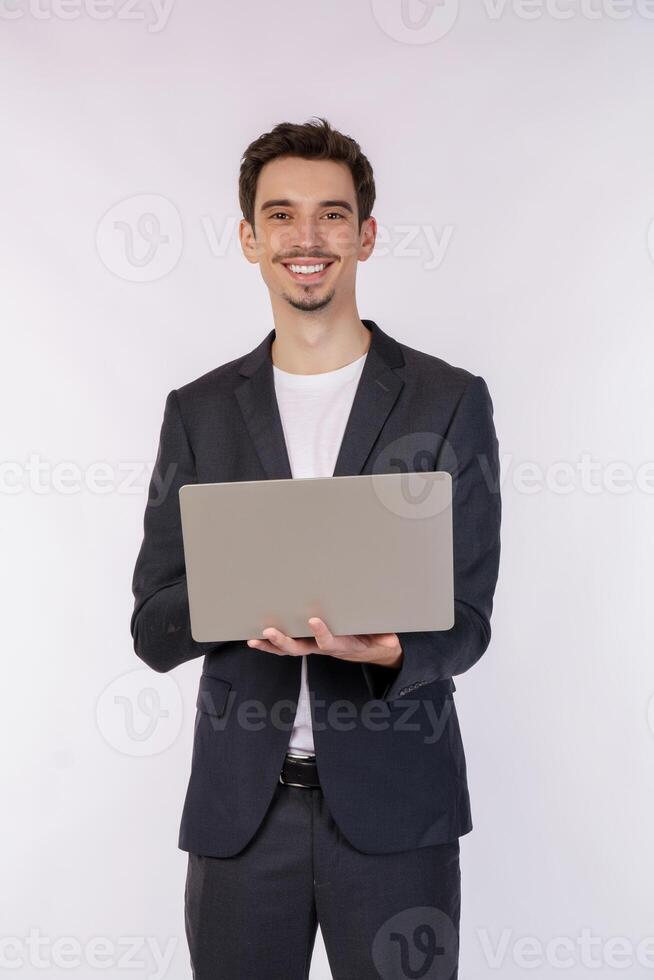 Portrait of young handsome smiling businessman holding laptop in hands, typing and browsing web pages isolated on white background photo