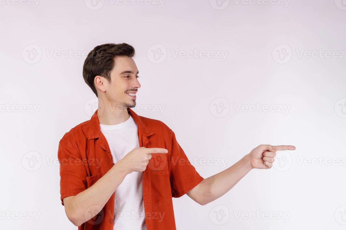 Portrait of young man pointing fingers at copy space isolated on white studio background photo