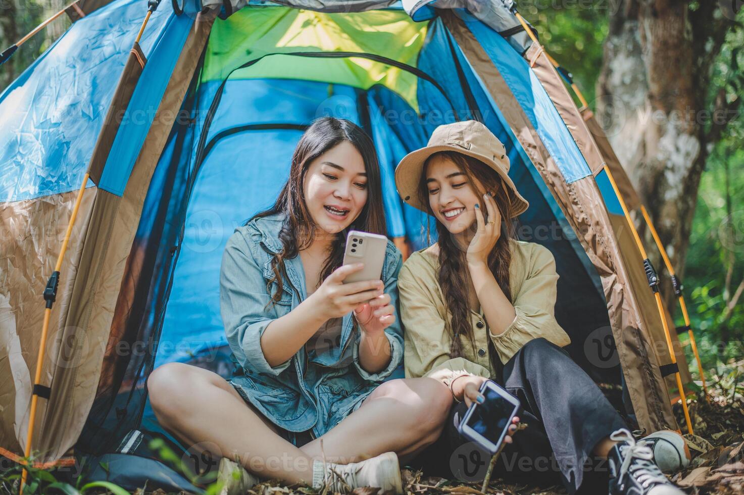 Asian pretty woman and friend use smartphone selfie on camping photo