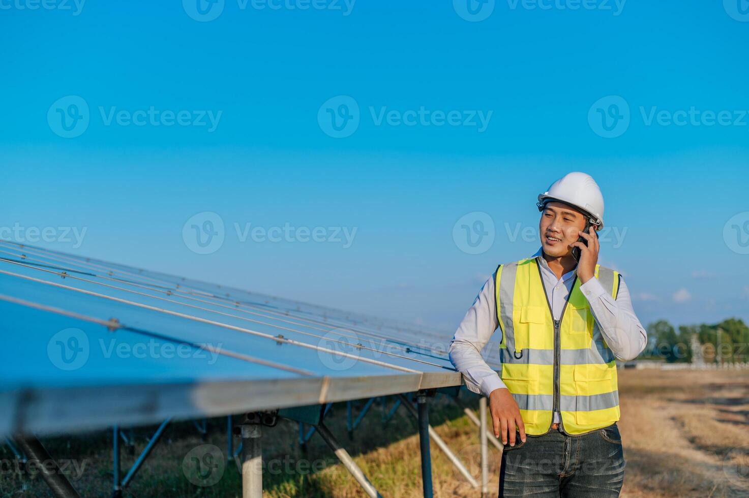 joven ingeniero usa un teléfono inteligente mientras trabaja en una granja solar foto