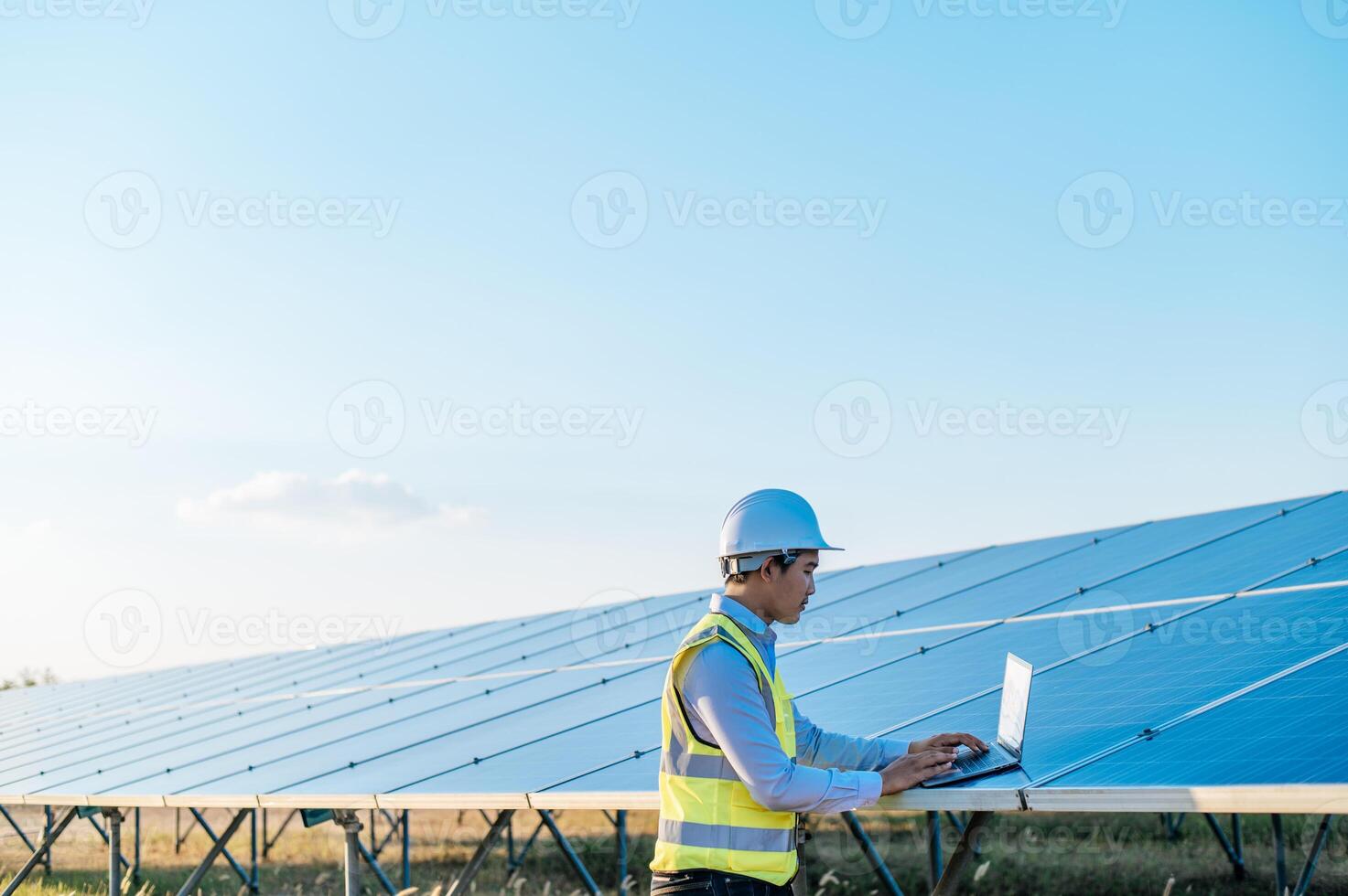 Young technician man working on laptop in solar farm photo