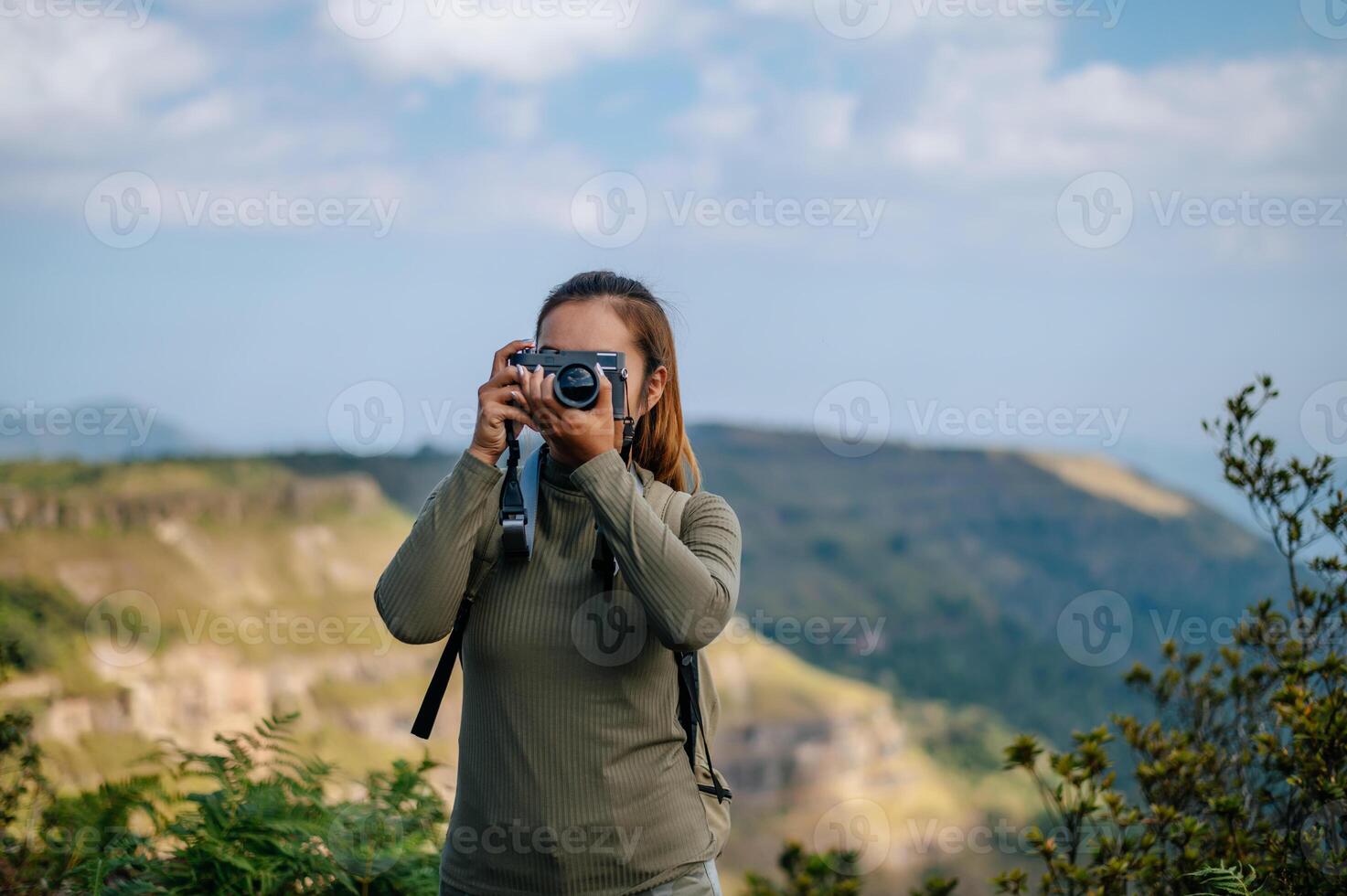 joven trekking hembra utilizar cámara fotografía en rocoso montaña pico foto