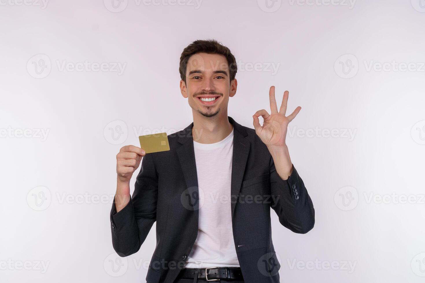Portrait of Young smiling handsome businessman showing credit card and ok sign hand isolated over white background photo
