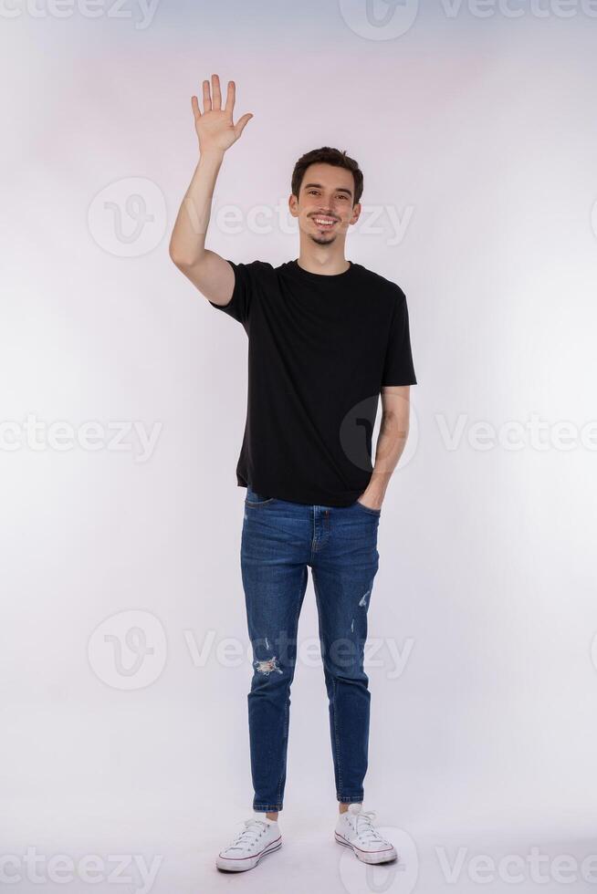 Portrait of friendly cheerful man in black t-shirt and jeans saying hi, welcome person as waving hand photo
