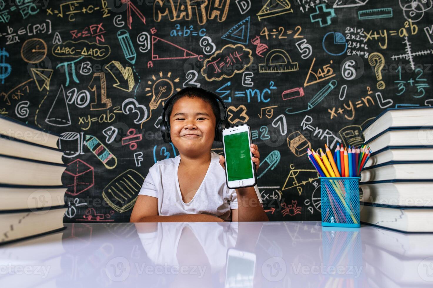Child sitting and showing mobile in the classroom photo