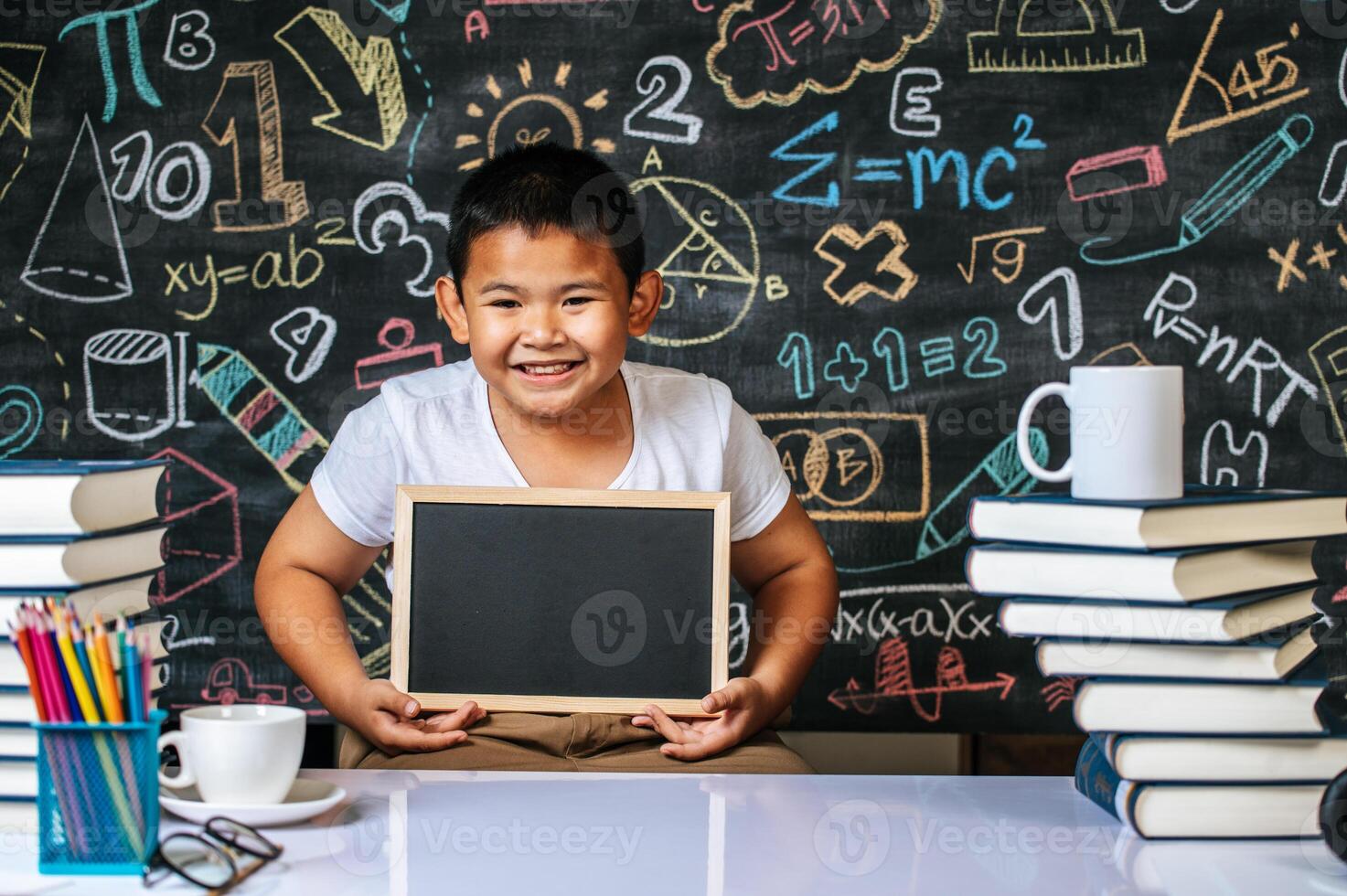 Child standing and holding blackboard in the classroom photo