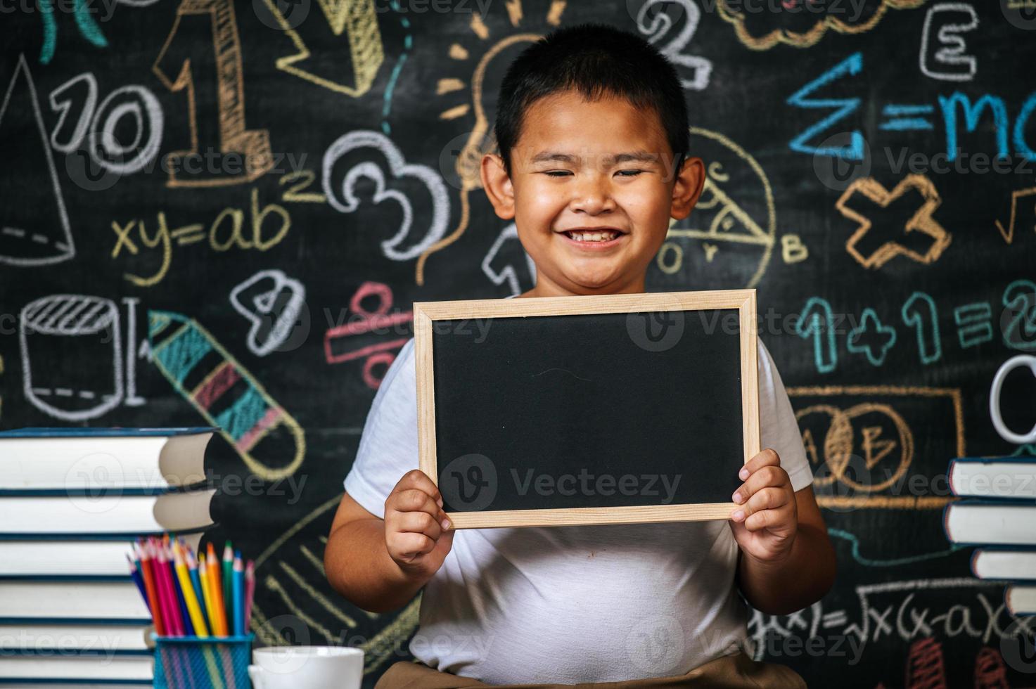Child standing and holding blackboard in the classroom photo