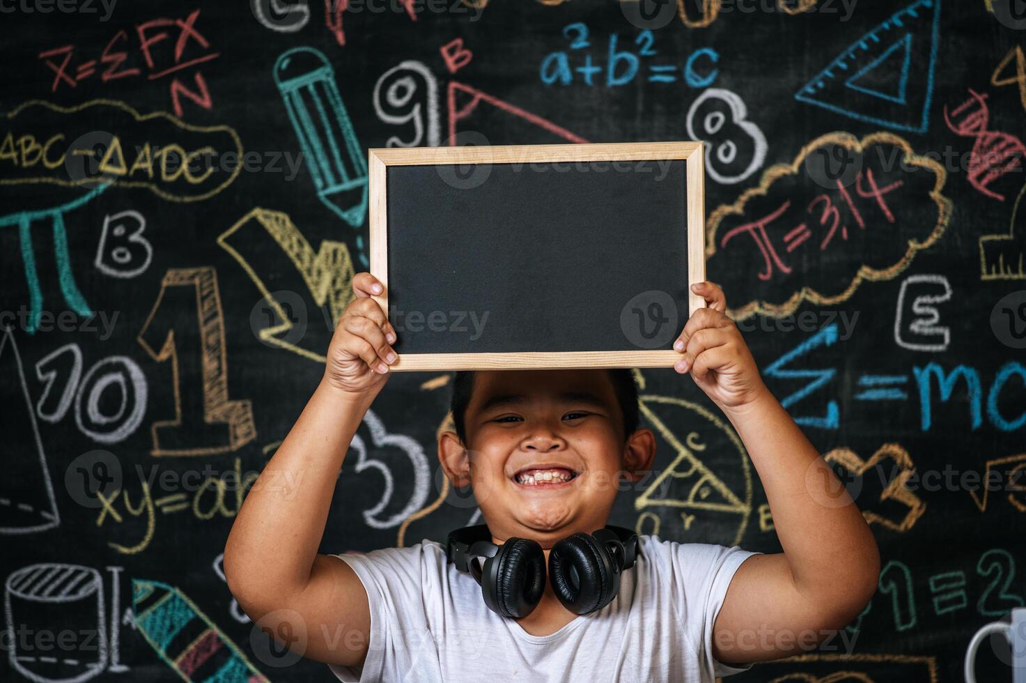 Child sitting and holding blackboard in the classroom photo