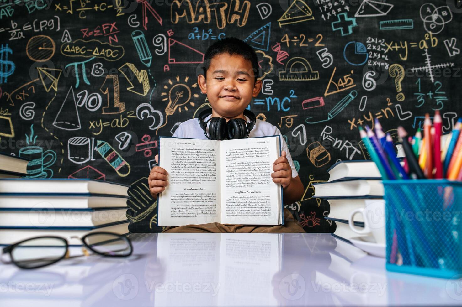 Child sitting and showing book in the classroom photo