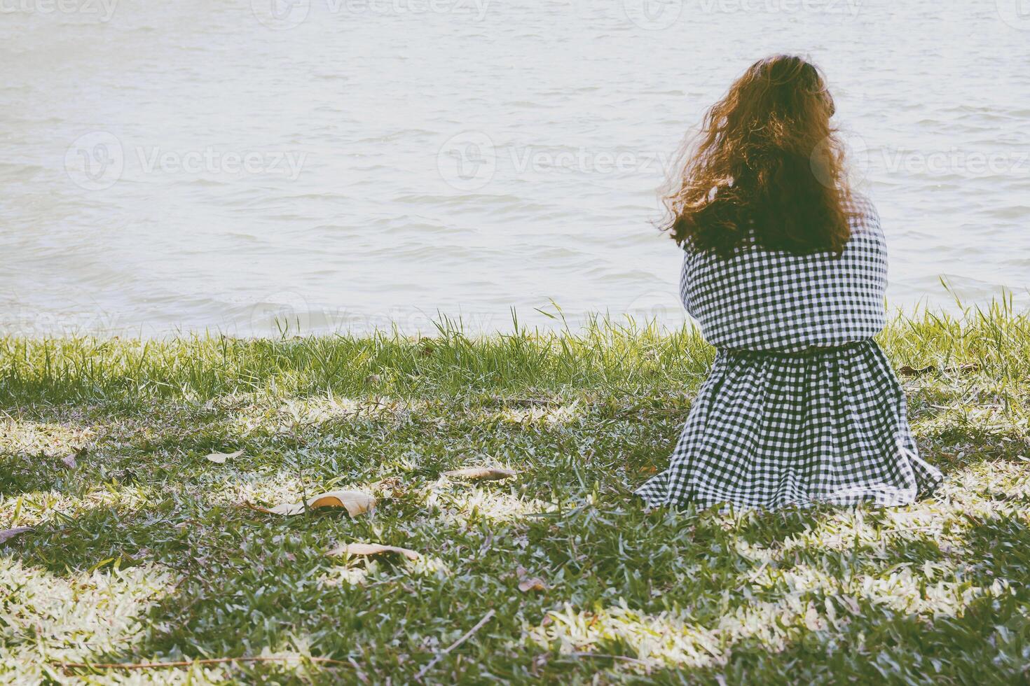 Backside of woman sitting near lake. photo