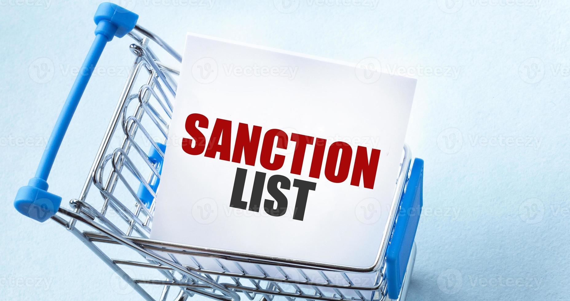 Shopping cart and text sanction list on white paper note list. Shopping list concept on blue background. photo