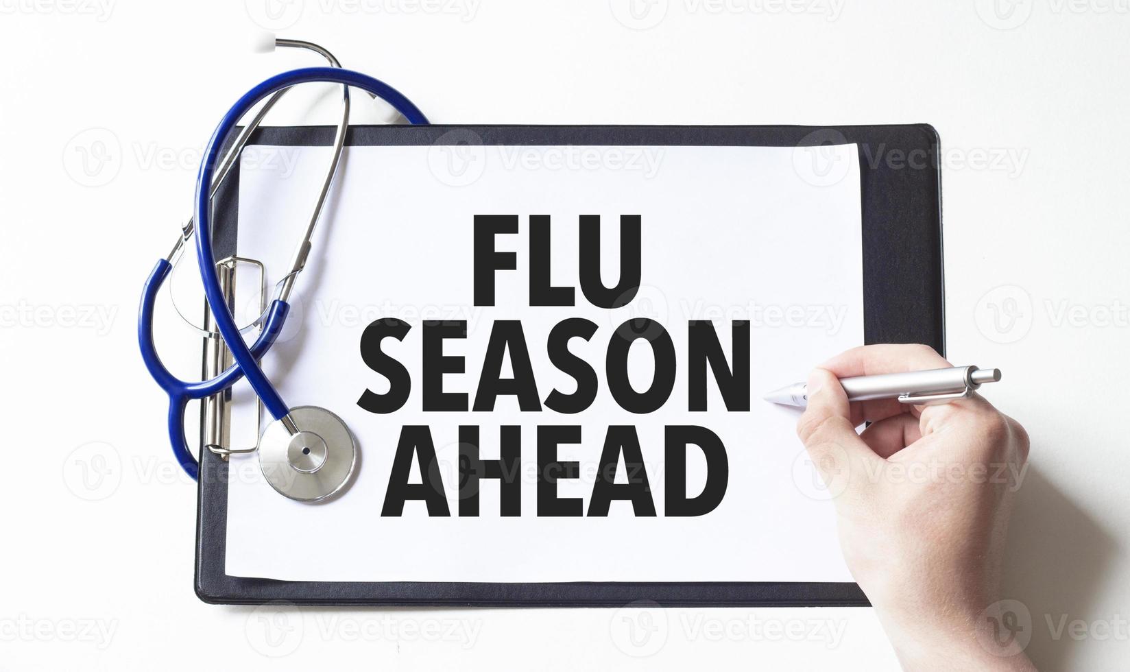 Doctor holding a pen and card with text flu season ahead, medical concept photo