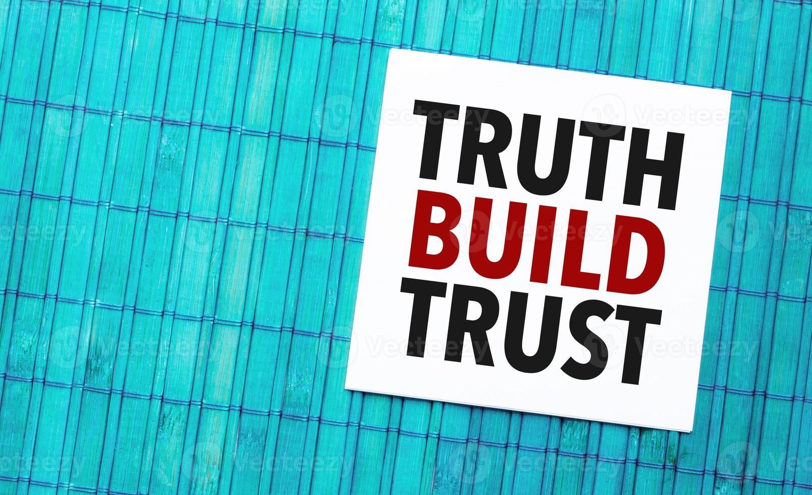 truth build trust word on torn paper with blue wooden background photo