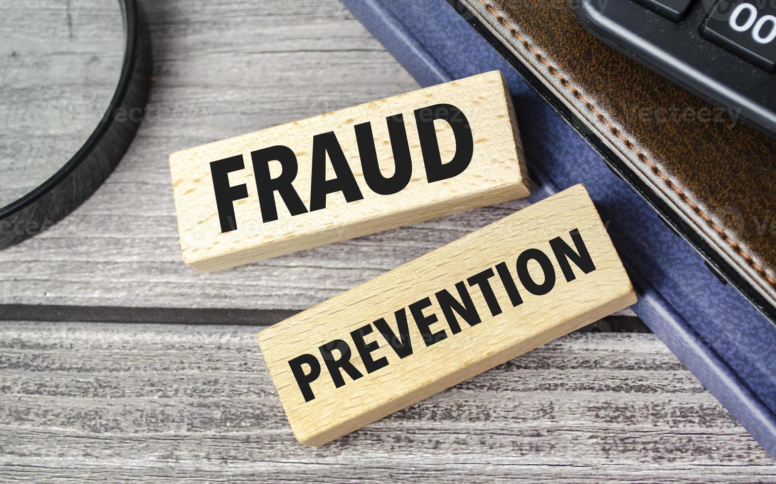 fraud prevention . text on wooden blocks on wooden background with office supplies photo