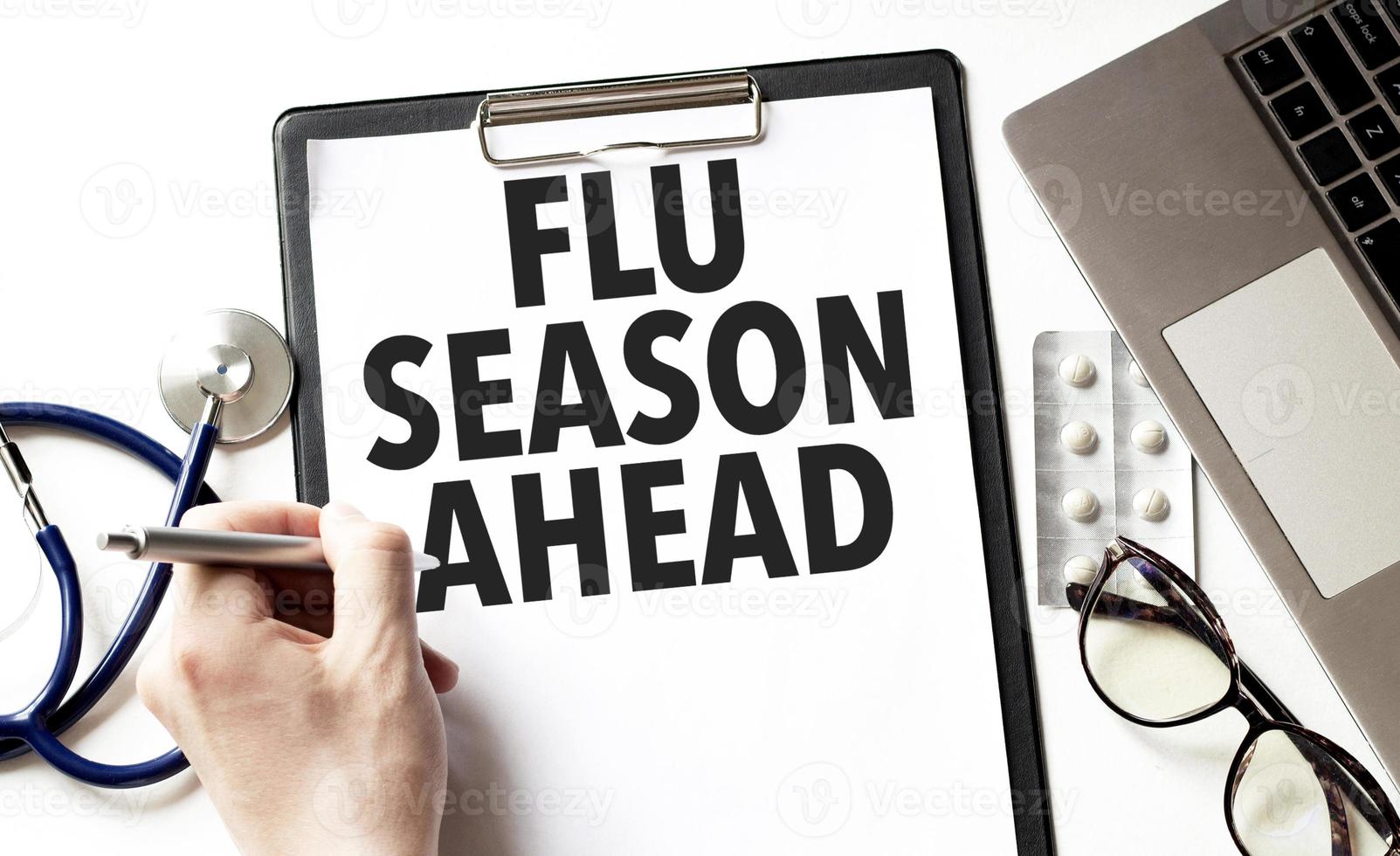 Doctor holding a pen and card with text flu season ahead, medical concept photo