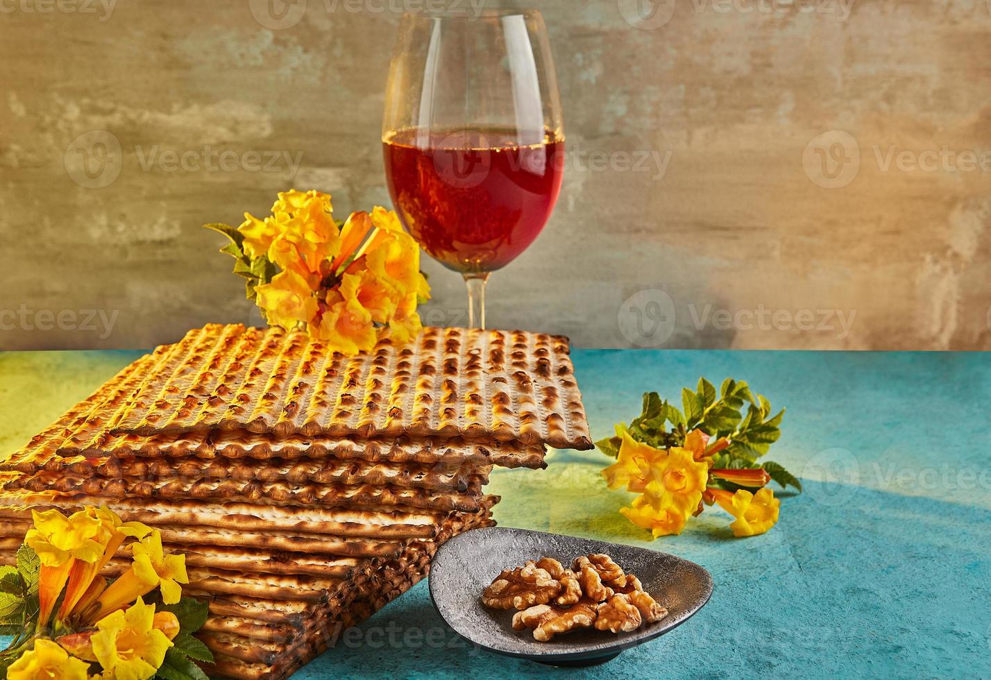 Pesach celebration concept - Jewish holiday Pesach. Background with yellow flowers with glass of wine, matzah and plate of seder in the rays of the sun. Traditional Jewish inscriptions on plate photo