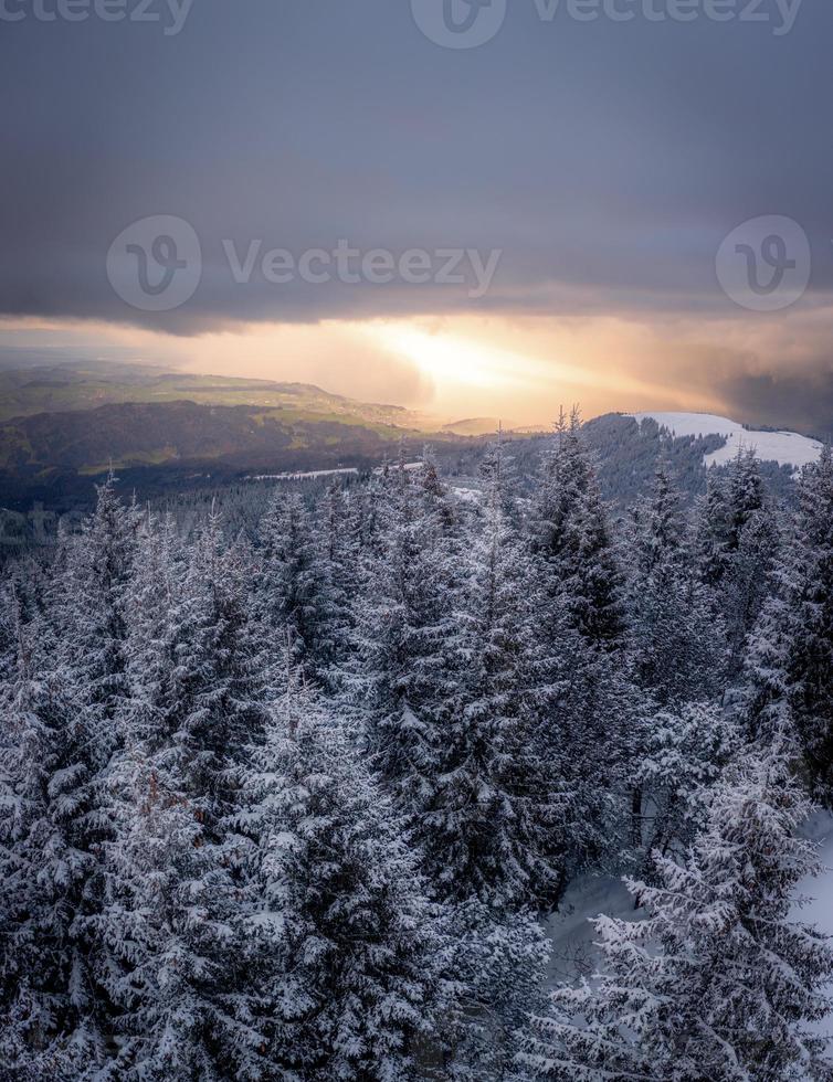 A winter landscape with a view into the valley, The clouds are broken and a sunbeam breaks through photo