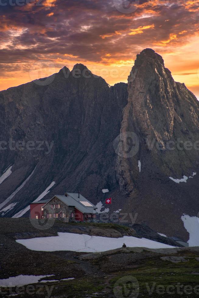 suizo montaña casa de huespedes en el parte superior de el montaña , con dramático puesta de sol foto