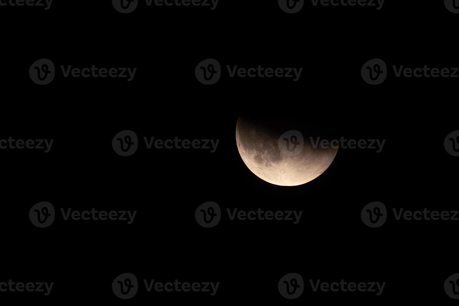 a lunar eclipse the moon is half visible,the background is black photo