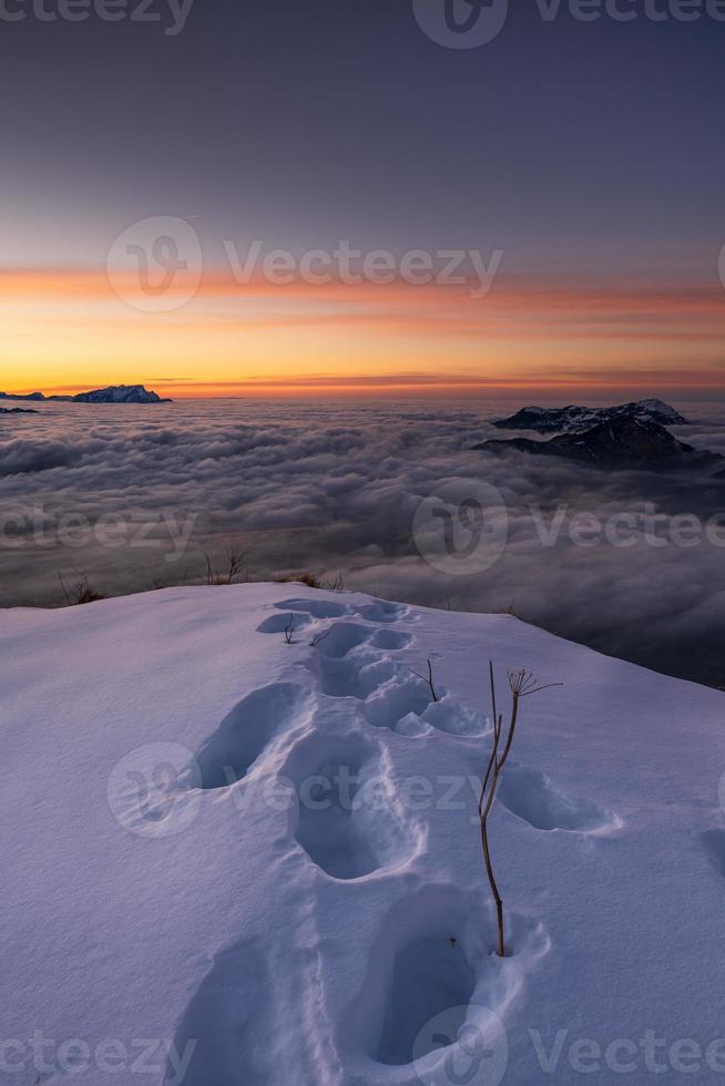 Winter landscape on top of a mountain during a sunset with shoe prints in snow photo