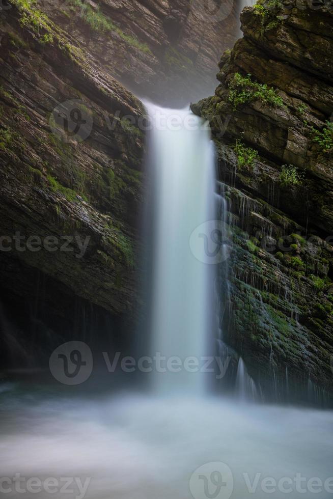 A mystical waterfall flowing from a cave photo