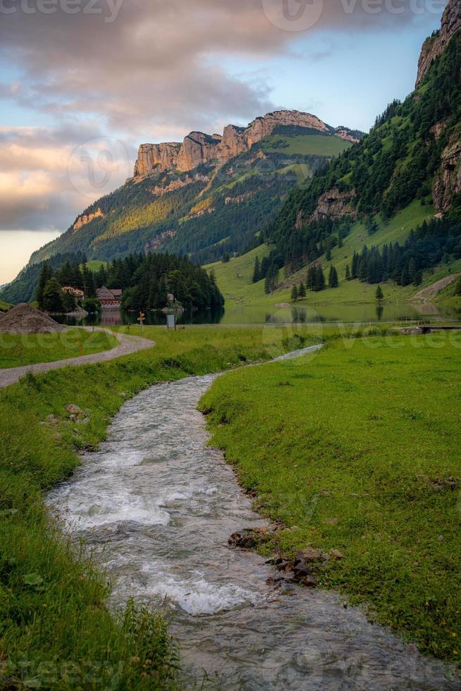 A small stream surrounded by mountains at sunset photo