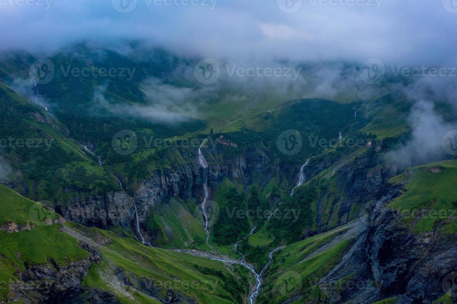 Aerial shot of several large waterfalls cascading down a steep cliff photo