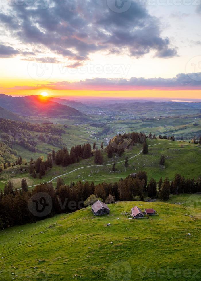 a farm high on the hills during a sunset in the distance you can see a hilly landscape photo