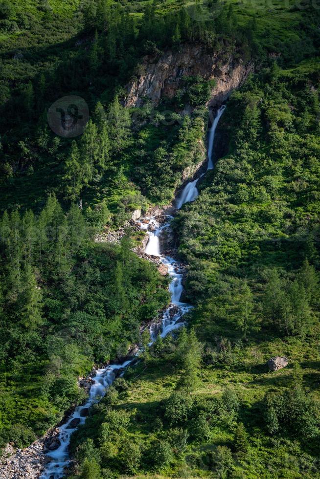 A waterfall running down the mountain photo