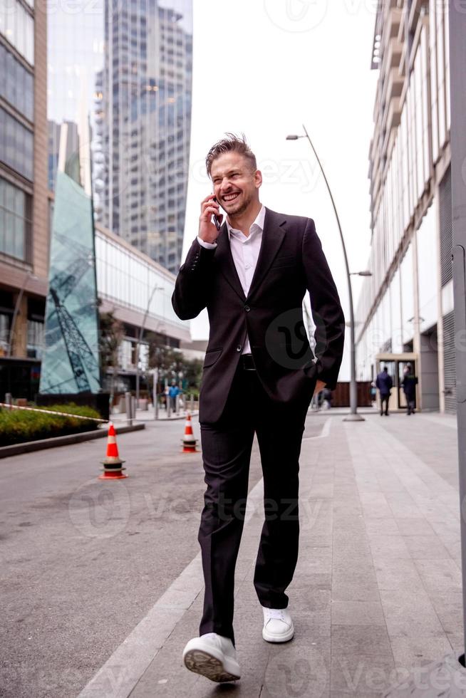 guy in a suit talks on the phone laughs and walks photo
