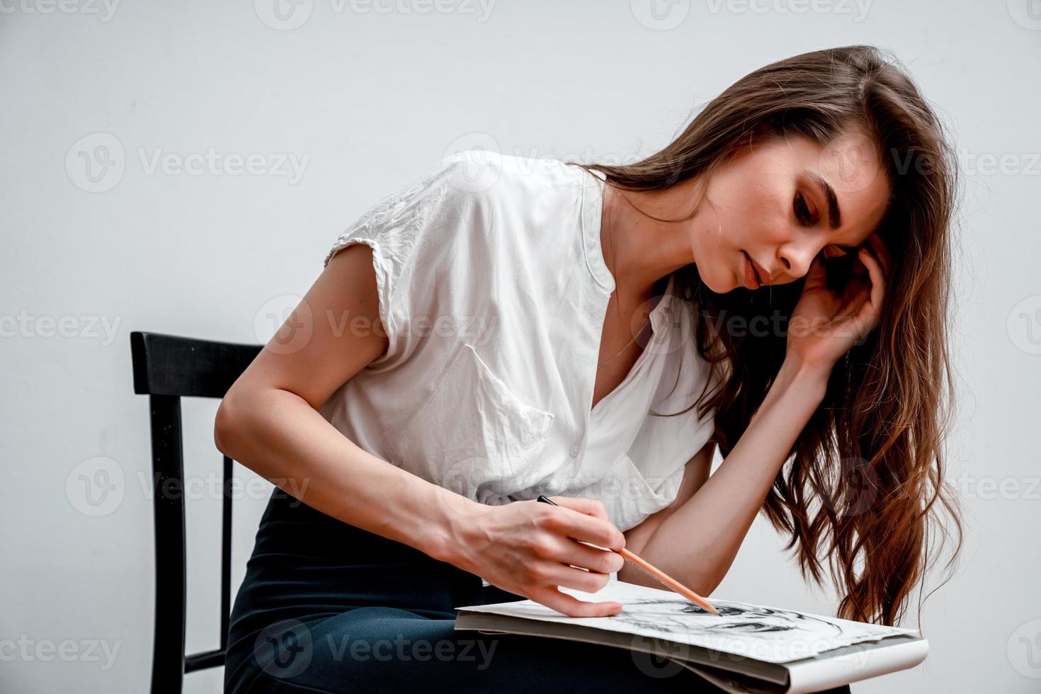 Girl sitting on a chair draws a sketch for a picture photo