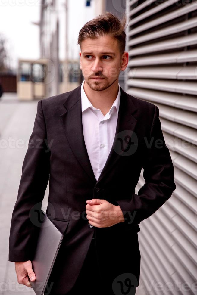 Portrait of a young businessman in a business center with a laptop in his hands photo