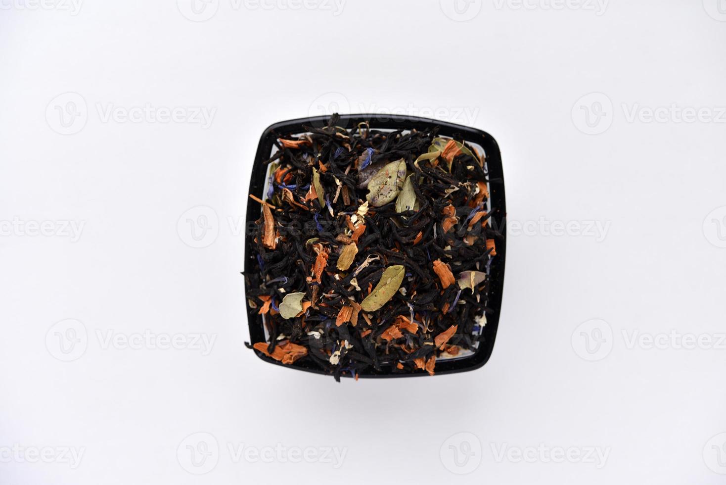 Black tea with spices in a glass cup on a white background. Delicious tea. Dry tea. photo