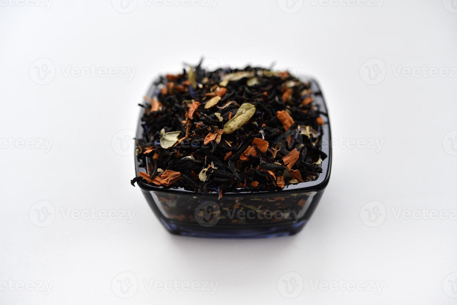 Black tea with spices in a glass cup on a white background. Delicious tea. Dry tea. photo