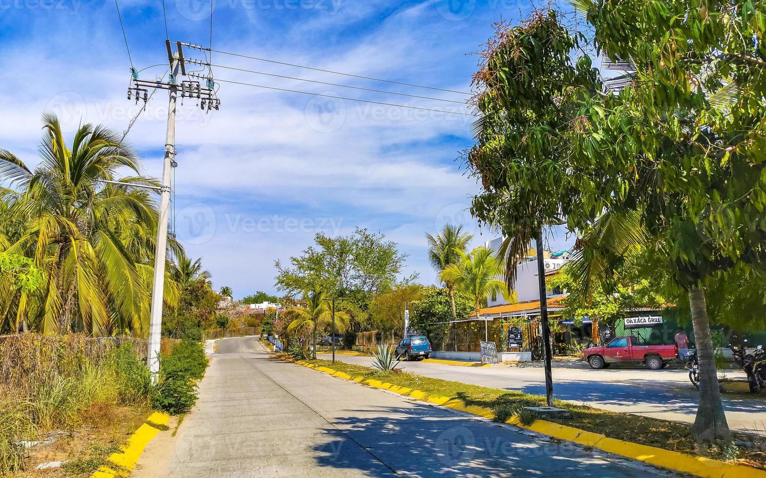 Colorful street with houses palms cars restaurants Puerto Escondido Mexico. photo
