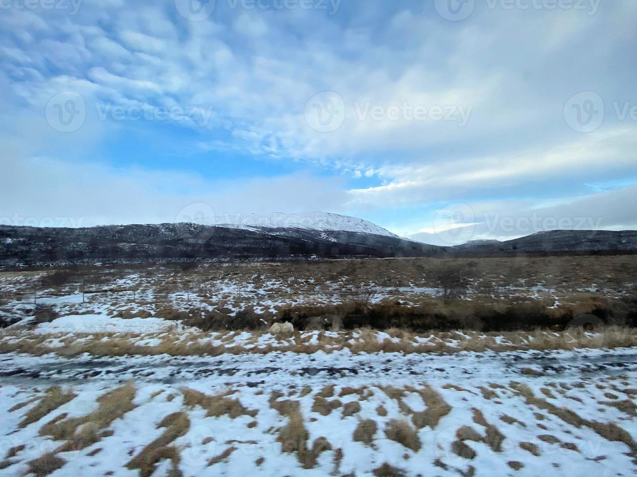 Icelandic winter landscape with snow covered hills and blue cloudy sky photo