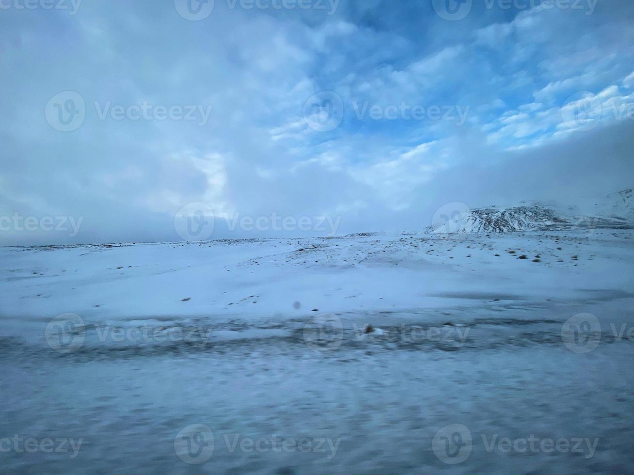 Icelandic winter landscape with snow covered hills and blue cloudy sky photo
